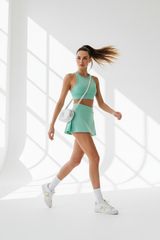 Women's sporty wrap mini skirt set in mint green, dynamic walking pose