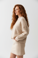 Women's knitted mini skirt set in cream beige, side profile pose