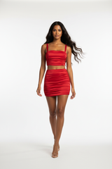 Women's ruched mini skirt set in bold red, dynamic walking pose