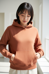 Luxury pullover hoodie in Dusty Terracotta, detail close-up of kangaroo pocket and fleece texture